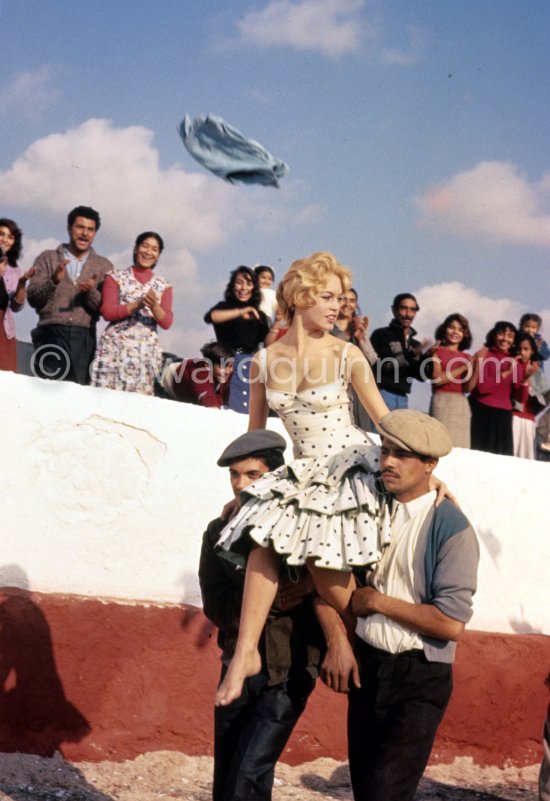 Brigitte Bardot during filming of the last scenes of "Les Bijoutiers du clair de lune" ("The Night Heaven Fell"), on the grounds of the Studios de la Victorine in Nice. Directing the film is Brigitte’s ex-husband Roger Vadim. Brigitte is carried by two Romani. The scene is supposed to represent Brigitte being carried victoriously out of the bull ring, after having given battle to a bull. All people in the back, young and old, are Romani. Nice 1958. - Photo by Edward Quinn