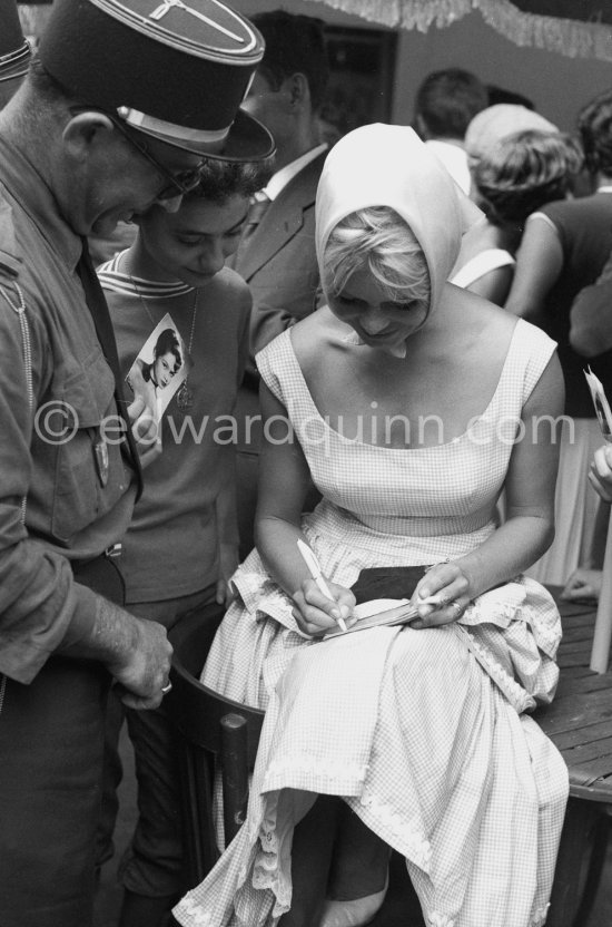 Brigitte Bardot signing a set card for a gendarme. Saint-Tropez 1958. - Photo by Edward Quinn