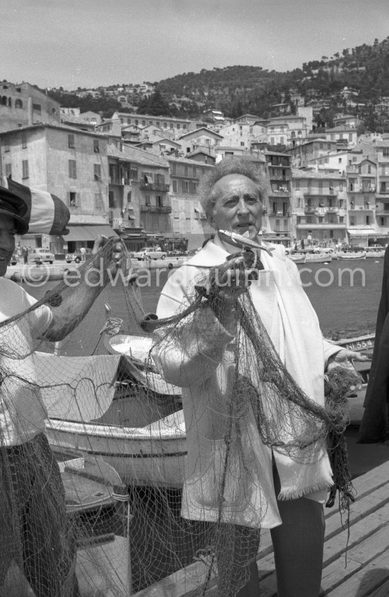 On the docks of the harbor at Villefranche-sur-Mer Jean Cocteau receives in a fishnet a life-size gold sardine from fisherman Paul Dunan, known as \'\'The Pirate\'\'. This present, created by a Nicois jeweller, is from the fishermen as a thank-you for the restoration and decoration works undertaken by the writer on the Chapelle Saint Pierre. Villefranche-Sur-Mer 1959. - Photo by Edward Quinn