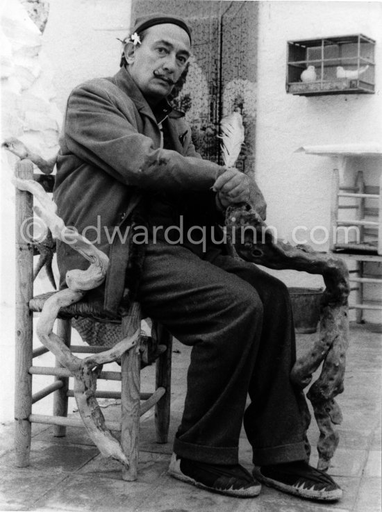 Salvador Dalí sits on one of the chairs which he has decorated with wooden branches swept in from the sea. Portlligat, Cadaqués, 1957. - Photo by Edward Quinn