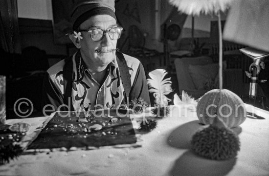 Salvador Dalí with his sea urchins. A swan\'s feather he puts in the sea urchin\'s mouth is allowed to slightly touch a sheet of blackened paper. The movements then made are traced on the paper. At Salvador Dalí\'s house, Portlligat, Cadaqués 1957. - Photo by Edward Quinn