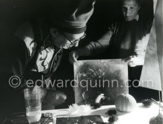 Watched by his wife Gala, Salvador Dalí works on his experiments with the sea urchin holding a swan feather and moving backwards and forewards thus marking the blackened paper. These experiments he is carrying out at his atelier in his Spanish home at Portlligat, Cadaqués, on the Costa Brava 1957. - Photo by Edward Quinn
