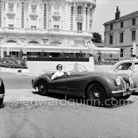 Clark Gable and "fiancée" Suzanne Dadolle, French model, in front of Carlton Hotel. Cannes 1953. Car: 1951  Jaguar XK120 OTS Battleship grey/red, Car today see https://bit.ly/3kLirWW - Photo by Edward Quinn