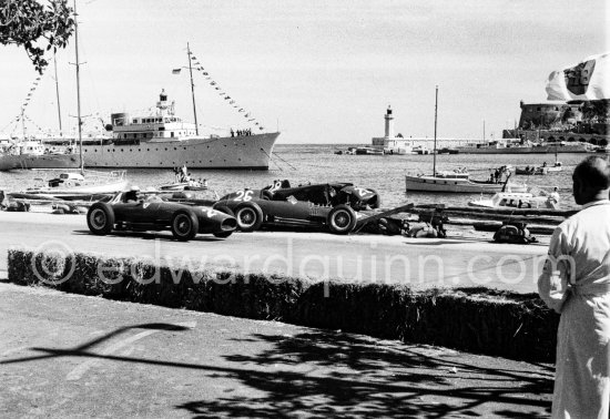 The cars of Mike Hawthorn, (28) Ferrari-Lancia D50 and Peter Collins, (26) Ferrari 801 in the barriers while Wolfgang von Trips, (24) Ferrari 801, passes. Yacht Trenora in the background. The incident happend in lap 4 of the 1957 Monaco Grand Prix after leader Stirling Moss "lost" his Vanwall in the chicane. Peter Collins swerved to avoid Moss but hit the wall while Mike Hawthorn rammed Tony Brooks who braked hard to avoid the cars in front of him. - Photo by Edward Quinn