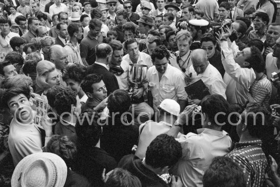 Graham Hill, talking with Raymond Mays (white shirt and dark jacket), co-founder of B.R.M., left Louis Stanley "Big Lou", B.R.M. chairman, his wife (helmet coiffure) on left, right of her Bette Hill. Monaco Grand Prix 1965. - Photo by Edward Quinn