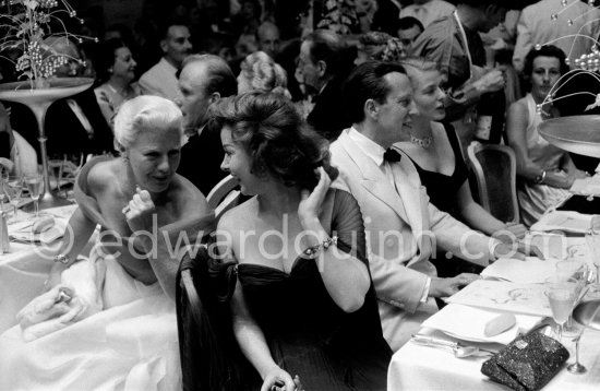 Susan Hayward and Ginger Rogers in animated conversation during the closing gala dinner at Cannes Film Festival. Behind them Ingrid Bergman and the Cannes Festival founder and president Robert Favre Le Bret. During the closing gala dinner. Cannes 1956. - Photo by Edward Quinn