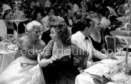 Susan Hayward and Ginger Rogers in animated conversation during the closing gala dinner at Cannes Film Festival. Behind them Ingrid Bergman and the Cannes Festival founder and president Robert Favre Le Bret. During the closing gala dinner. Cannes 1956. - Photo by Edward Quinn