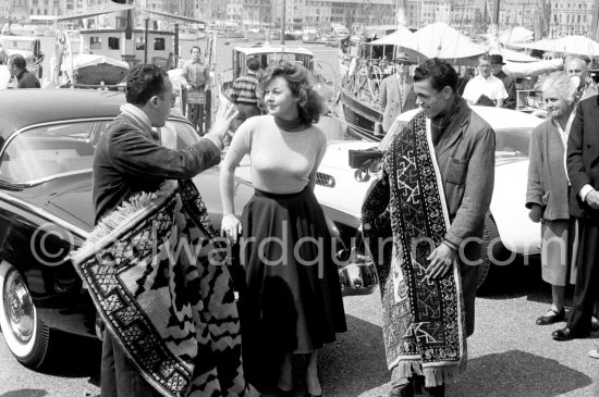 Foreign carpet sellers trying to convince Susan Hayward to acquire one of these beautiful pieces. Cannes Film Festival 1956. - Photo by Edward Quinn