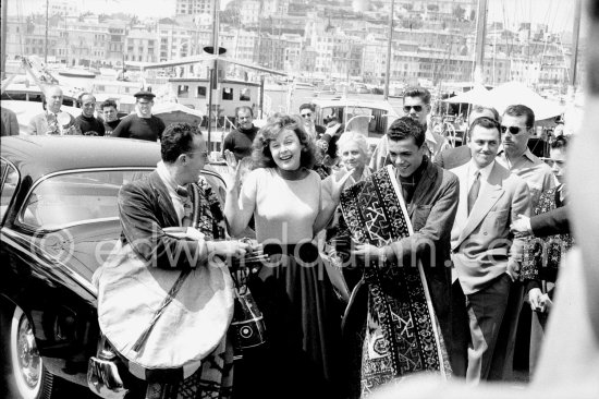 Foreign carpet sellers trying to convince Susan Hayward to acquire one of these beautiful pieces. Cannes Film Festival 1956. Car: Studebaker - Photo by Edward Quinn