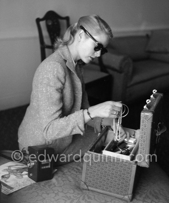 Grace Kelly, in Cannes for the Film Festival, putting her jewellery away safely in her room at the Carlton Hotel. Cannes 1955. Cartier Trinity ring, Rolleiflex camera - Photo by Edward Quinn