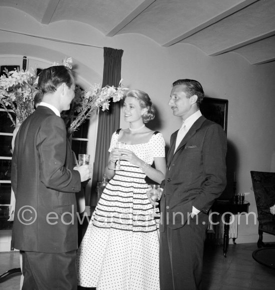 Grace Kelly at a cocktail party given by Jacques Fath at his home “Moulin de Joko”. On the left celebrity promoter Earl Blackwell and American fashion designer Oleg Cassini (right). Cannes 1954. - Photo by Edward Quinn