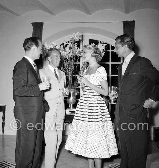 Grace Kelly at a cocktail party given by Jacques Fath (second from left) at his home “Moulin de Joko”. On the left celebrity promoter Earl Blackwell and right American fashion designer Oleg Cassini. Cannes 1954. - Photo by Edward Quinn