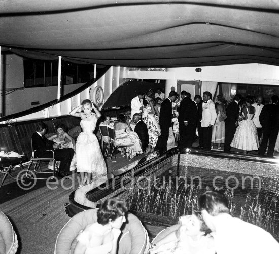 Tina Onassis, on the left, behind her Eugenie Niarchos. Cocktail on Onassis\' yacht Christina. Monaco harbor 1957. - Photo by Edward Quinn