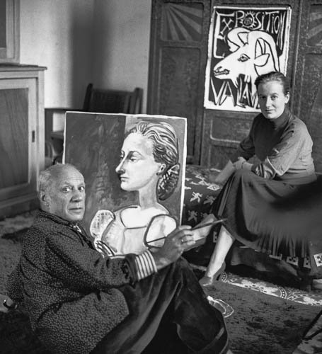 Picasso with Irène Rignault (Madame X) and the portrait of her in October 1953. This painting valued at that time at 500\'000 FF was later stolen from the property of Mme Madeleine Roger, mother of Mme Rignault at Bellerive-sur-Allier or sold by her. In the background an automatic piano which Picasso bought 1950 in a bistro in Vallauris. La Galloise, Vallauris Oct 1953. - Photo by Edward Quinn