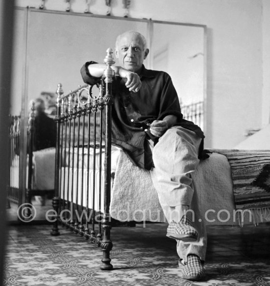 Pablo Picasso completely at ease, with baggy, unpressed trousers, a very loose-fitting shirt, and carpet slippers, in his bedroom at La Galloise, Vallauris 1954. - Photo by Edward Quinn