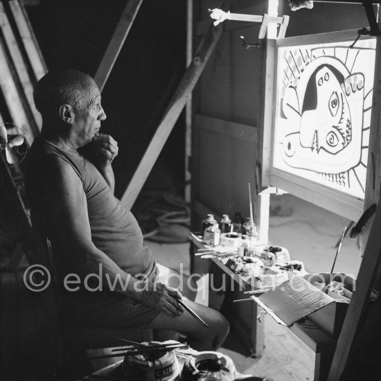 During filming of "Le mystère Picasso". Pablo Picasso working on "Tête de femme" with colored ink. He had a frame constructed on which he could stretch a transluscent piece of paper. He drew on one side, and the camera filmed the drawing being born from the other side. Nice, Studios de la Victorine 1955. - Photo by Edward Quinn