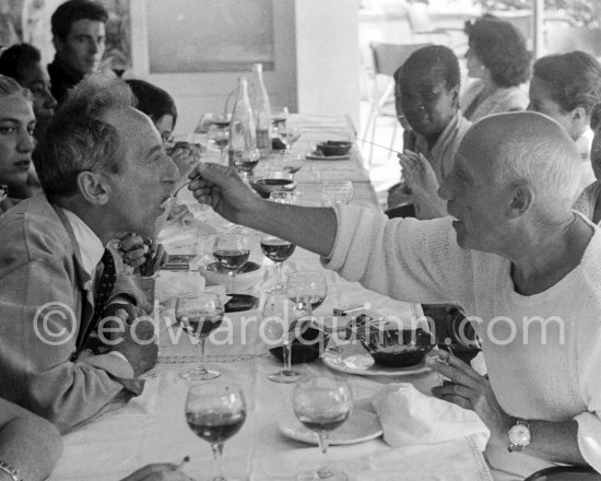 Pablo Picasso feeding Jean Cocteau at the lunch given for his friends at restaurant Le Vallauris before the bullfight. Vallauris 1955. - Photo by Edward Quinn