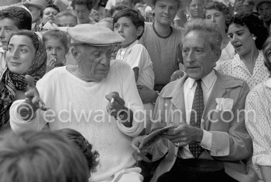 On the grandstand of a bullfight put on in Pablo Picasso\'s honor. Pablo Picasso strikes a funny attitude then telling comfortable that he has no pencil to sign autographs. On the left of Pablo Picasso Jacqueline, on the right Jean Cocteau, behind Pablo Picasso his children Paloma Picasso and Claude Picasso. Vallauris 1955. - Photo by Edward Quinn