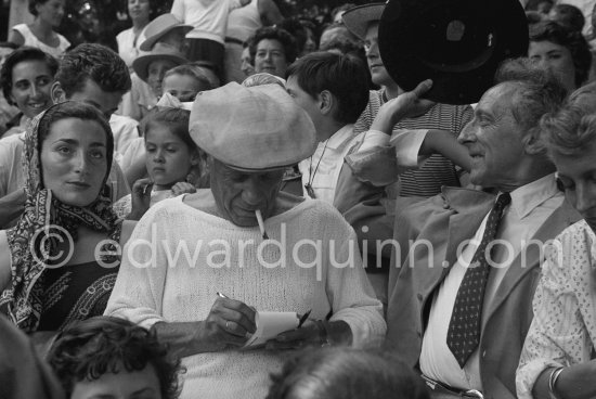 On the grandstand of a bullfight put on in his honor, Pablo Picasso is signing autographs. On the left Jacqueline, on the right Jean Cocteau. Vallauris 1955. - Photo by Edward Quinn