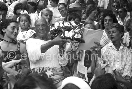 Pablo Picasso on the grandstand at the corrida with a bull sculpture, a present from the bullfighters ("A notre camarade Pablo Picasso, Section Vallauris, Corrida 1955."). Jacqueline, Maya Picasso, Claude Picasso, Paloma Picasso with a pendant by Pablo Picasso, Jean Cocteau, Francine Weisweiller. Vallauris 1955. - Photo by Edward Quinn