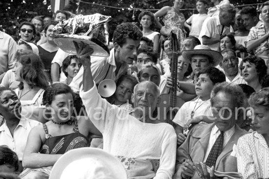 Pablo Picasso on the grandstand at the corrida with a bull sculpture, a present from the bullfighters ("A notre camarade Pablo Picasso, Section Vallauris, Corrida 1955."). Jacqueline with a brooch by Pablo Picasso, Claude Picasso, Paloma Picasso, Jean Cocteau, Francine Weisweiller. Vallauris 1955. - Photo by Edward Quinn