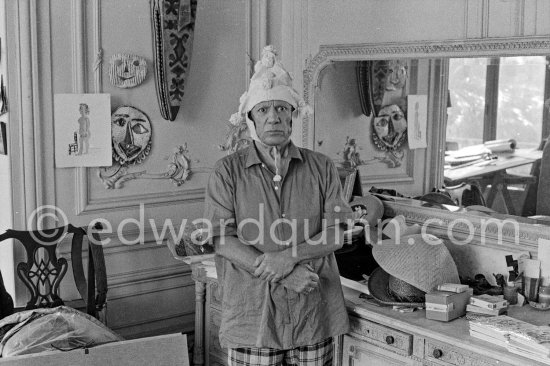 To strike a pose, Pablo Picasso tries on hats from his collection for his own amusement and that of his guests. La Californie, Cannes 1956. - Photo by Edward Quinn