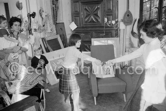 Paloma Picasso pulls a surprise cracker with Catherine Hutin. The Dominguin children and Inès Sassier, Pablo Picasso\'s housekeeper look on. The book open on the armchair shows a portrait of Paloma Picasso. Pablo Picasso, La Californie, Cannes 1959. - Photo by Edward Quinn