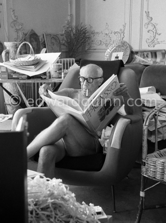 Pablo Picasso viewing a book on himself. A Ripolin can behind him on a table by Joseph-Marius Tiola. La Californie, Cannes 1961. - Photo by Edward Quinn