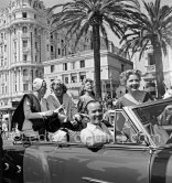 Out for a drive on La Croisette in front of Carlton Hotel, at the wheel Earl Blackwell, president of "Celebrity Service", sitting beside him the American actress Ann Baxter, at the very back Arletty. Cannes Film Festival 1953. - Photo by Edward Quinn