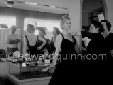 Zsa Zsa Gabor, trying on a frock, her husband George Sanders in the mirror. Carlton Hotel, Cannes 1963. - Photo by Edward Quinn