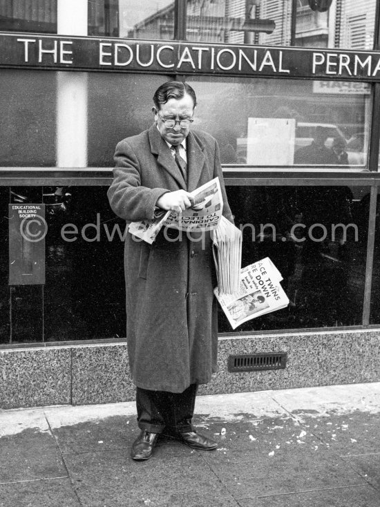 A news vendor in Westmoreland Street. Dublin 1963. Published in Quinn, Edward. James Joyces Dublin. Secker & Warburg, London 1974. - Photo by Edward Quinn