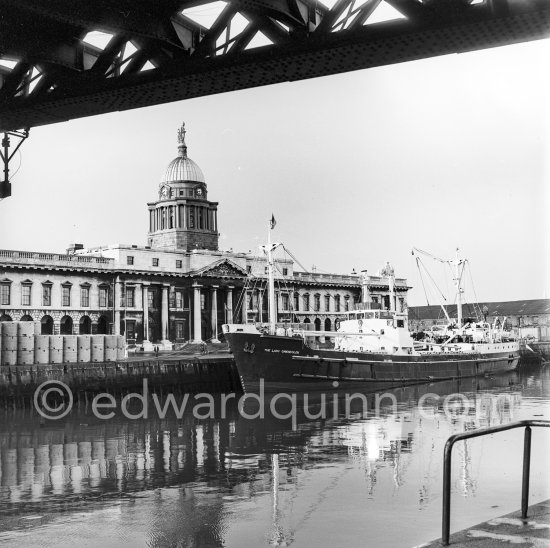 The River Liffey with Custom House, the Loop Line railroad Bridge above and a Guinness Brewery ship loading barrels. Dublin 1963. - Photo by Edward Quinn