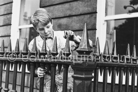Boy painting metal fence. Dublin 1963. - Photo by Edward Quinn