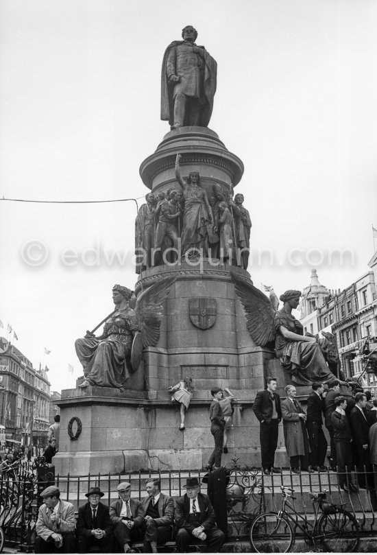 Waiting for President Kennedy to drive past during his visit. O\'Connell Monument, Bachelor\'s Walk / O\'Connell Street. Dublin 1963. - Photo by Edward Quinn