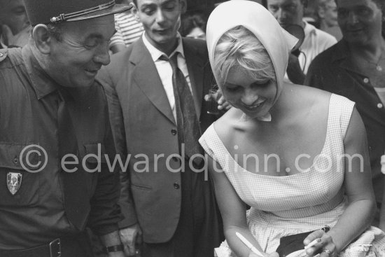 Brigitte Bardot signing a set card for a gendarme. Saint-Tropez 1958. - Photo by Edward Quinn