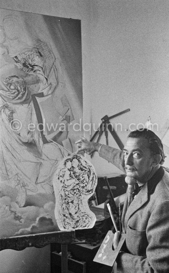 Salvador Dalí poses at his studio with his ink drawing of a madonna and her child and the painting "Cosmic Madonna", finished in 1958. At Salvador Dalí's house, Portlligat, Cadaqués, 1957. - Photo by Edward Quinn