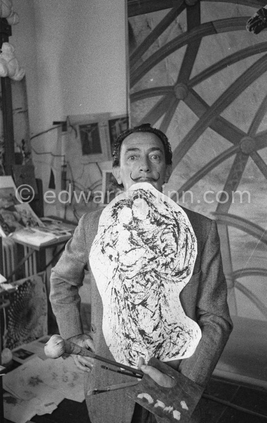 Salvador Dalí poses at his studio with his ink drawing of a madonna and her child and the painting "Cosmic Madonna", finished in 1958. At Salvador Dalí's house, Portlligat, Cadaqués, 1957. - Photo by Edward Quinn