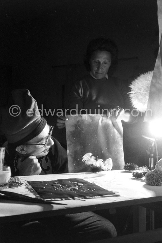 Watched by his wife Gala, Salvador Dalí works on his experiments with the sea urchin holding a swan feather and moving backwards and forewards thus marking the blackened paper. These experiments he is carrying out at his studio in his Spanish home at Portlligat, Cadaqués, on the Costa Brava 1957. - Photo by Edward Quinn