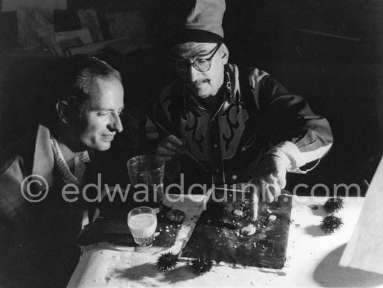 Dalí demonstrates his Canadian painter friend Philips the origin of the "oursin", a liquid which takes on a particular form. Here he is seen using milk and water. At Salvador Dalí\'s house, Portlligat, Cadaqués 1957. - Photo by Edward Quinn