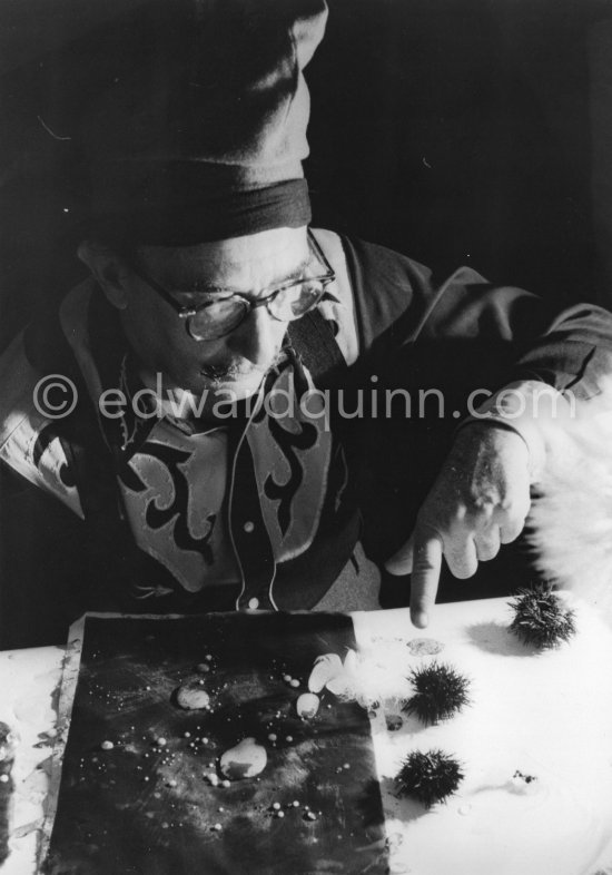 Salvador Dalí with his sea urchins. A swan\'s feather he puts in the sea urchin\'s mouth is allowed to slightly touch a sheet of blackened paper. The movements then made are traced on the paper. At Salvador Dalí\'s house, Portlligat, Cadaqués 1957. - Photo by Edward Quinn