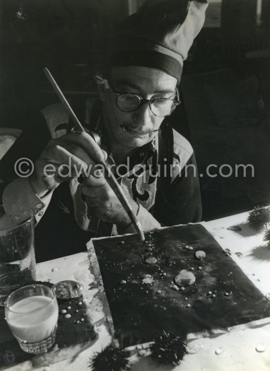 Dalí demonstrates the origin of the "oursin", a liquid which takes on a particular form. Here he is seen using milk and water. At Salvador Dalí\'s house, Portlligat, Cadaqués 1957. - Photo by Edward Quinn