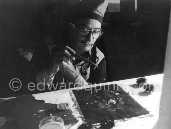 Salvador Dalí demonstrates the origin of the "oursin", a liquid which takes on a particular form. Here he is seen using milk and water. At Salvador Dalí\'s house, Portlligat, Cadaqués 1957. - Photo by Edward Quinn