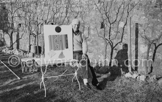 Max Ernst and Dorothea Tanning in the garden of her house at Seillans 1966. He holds the painting Schmetterling-Steuerzahler (papillon contribuable), for which he has used a piece of wallpaper, a flybat and a note from the income tax officer concerning his income tax return. - Photo by Edward Quinn