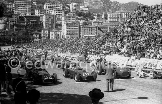 Front row left to right: Fangio, Collins, Moss
Motorsport Images
The front row of the grid saw the interesting sight of three completely different Grand Prix cars lined up, in the order Maserati, Lancia/Ferrari and Vanwall, driven, respectively, by Fangio, Collins and Moss. In row 2 were Brooks and Hawthorn, then came Trintignant, Menditeguy and Schell, followed by von Trips and Gregory. In row 5 were Flockhart, Gould and Lewis-Evans, row 6 Scarlatti and Brabham, and in solitary state at the back was Bueb.
There was a slight panic at the start when the Moss Vanwall refused to start on the starter and had to be pushed at the last moment, but all was well and as everyone jumped the starter’s flag the sixteen cars rushed away towards the Gasworks hairpin. For a moment the Vanwall hesitated as the wheels spun and then they gripped and Moss shot off into the lead, cutting smartly across from the left on the road to the right as he took the hairpin and successfully blocking Collins and Fangio who were about to try and push him off the line.
Everything seemed set for Moss to run right away from the rest of the field on the opening lap as he did last year with the Maserati, but though the Vanwall did not hang about, it could not shake the two rivals off. The roaring pack went by at the end of the opening lap in the order Moss, Fangio, Collins, Schell, Brooks, Menditeguy, Hawthorn, von Trips and the rest, and up the hill to the Casino Collins went past Fangio into second place.
Lap two saw the order unchanged, but Collins was closing on Moss, and the next lap saw Schell drop back behind von Trips and Brooks in fourth place. As the cars left the tunnel towards the end of the fourth lap Moss was only a few feet ahead of Collins, while Fangio was some way back, followed by Brooks, Hawthorn, von Trips, Schell, Menditeguy, and the others being led by Gould.
Juan Manuel Fangio (Maserati 250F), 1st position and Stirling Moss (Vanwall VW3), retired, lead at the start of the 1 - Photo by Edward Quinn