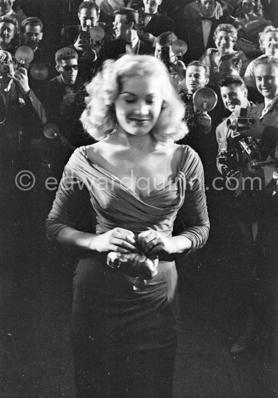 A photograph taken by a professional photographer who photographs a crowd of photographers who wait to take a photograph of Eliane Guy. Cannes Film Festival 1957. - Photo by Edward Quinn