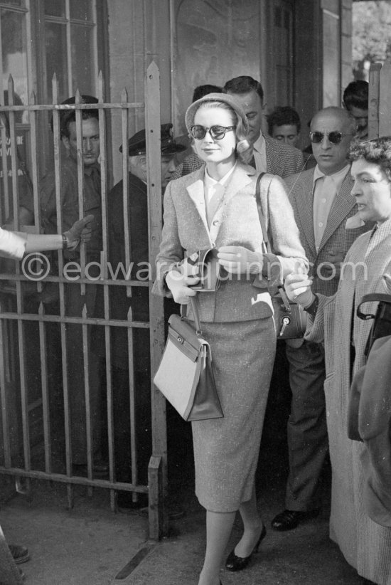 Grace Kelly with the original Kelly Bag and her Rolleiflex camera arriving at Cannes station 1955. - Photo by Edward Quinn