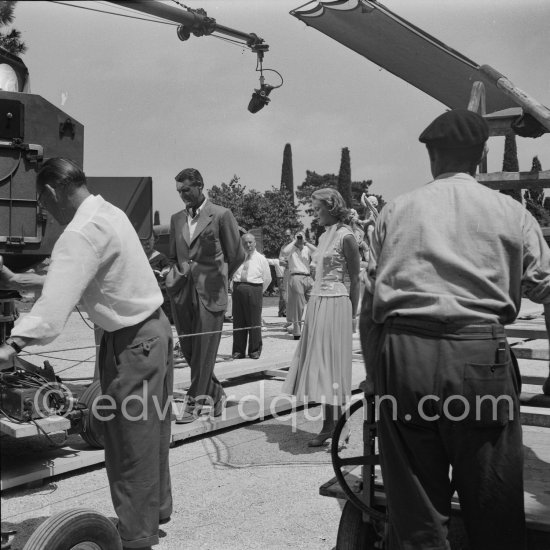 A love affair: Grace Kelly and Cary Grant on the film set of "To Catch a Thief". Alfred Hitchcock in the background. Cannes 1954. - Photo by Edward Quinn