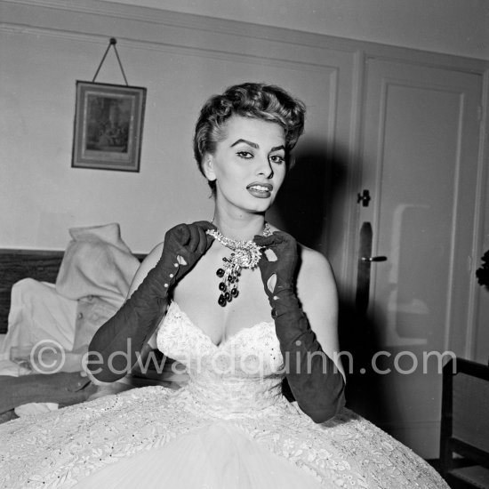 Sophia Loren in her Carlton Hotel room during the Cannes Film Festival wearing an evening gown designed by Emilio Schuberth, 27 April 1955. - Photo by Edward Quinn