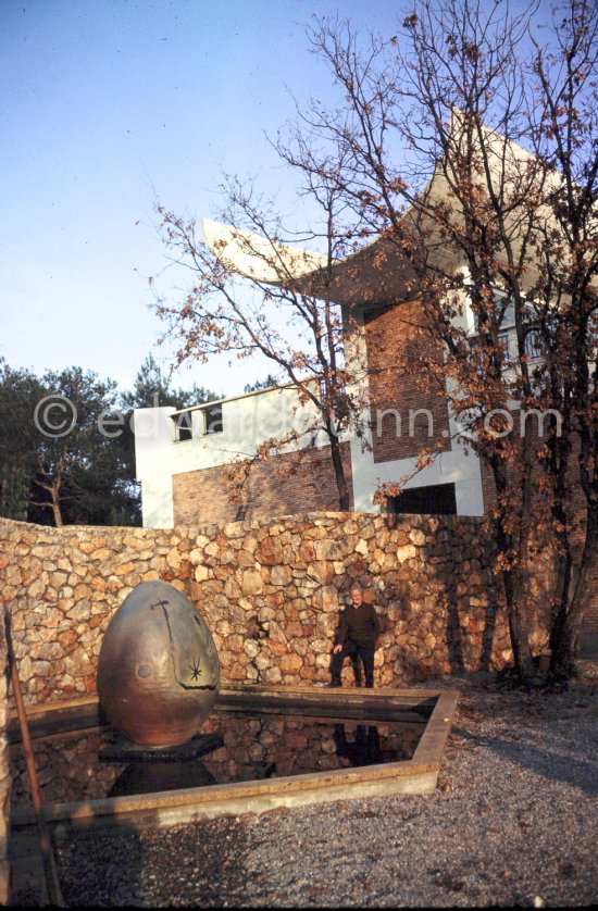 Joan Miró in the gardens of Musée Maeght in front of a small pool with an "Oeuf cosmique" by Miró in center. Saint-Paul-de-Vence 1964. - Photo by Edward Quinn