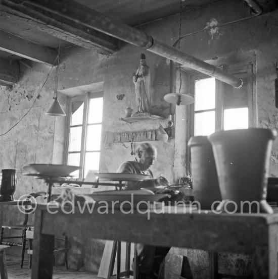 Pablo Picasso at work at the Madoura pottery in Vallauris. Above him is a statue of St-Claude, the patron saint of the potters, whose name was given to Pablo Picasso's younger son. Vallauris 23.3.1953. - Photo by Edward Quinn